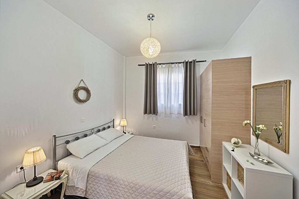 a white bedroom with a bed and a mirror at Aeolia apartments in Ermoupoli