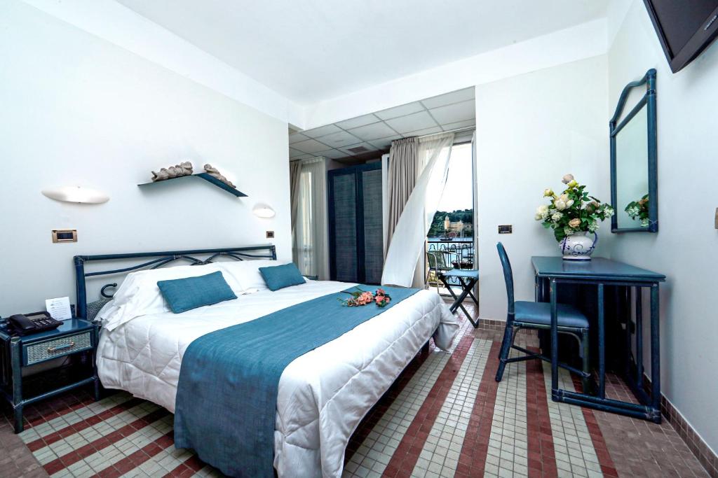 a hotel room with a large bed and a desk at Hotel Della Baia in Portovenere