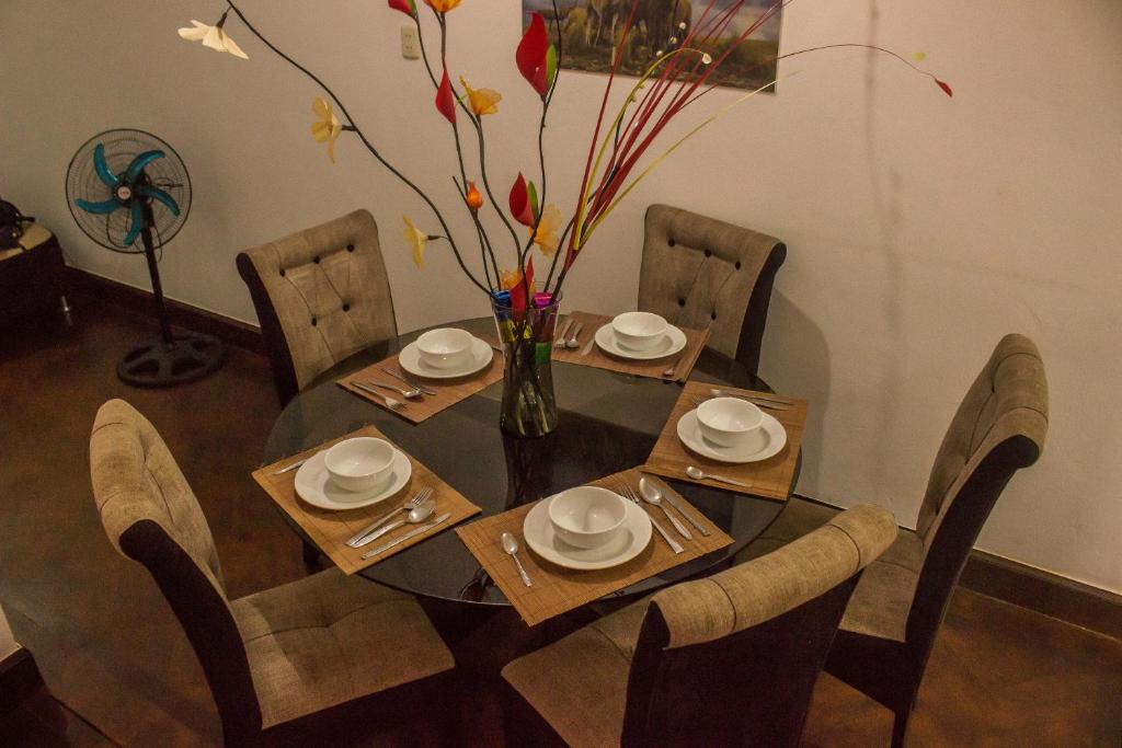 a dining room table with chairs and a vase with flowers at APARTMENT FOR GROUP Miraflores in Lima