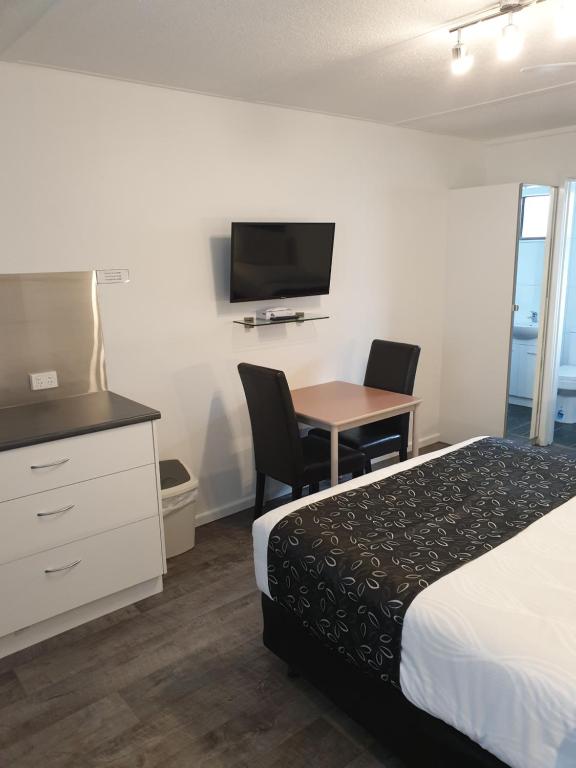 a hotel room with a bed and a desk and a tv at Budget on the Lake in Hamilton