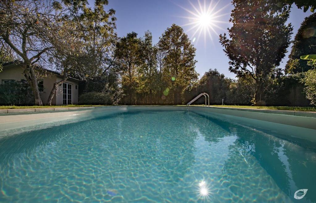 una piscina con el sol en el fondo en Villa Liberty 1927 heated pool, 2 miles Lucca, en Capannori