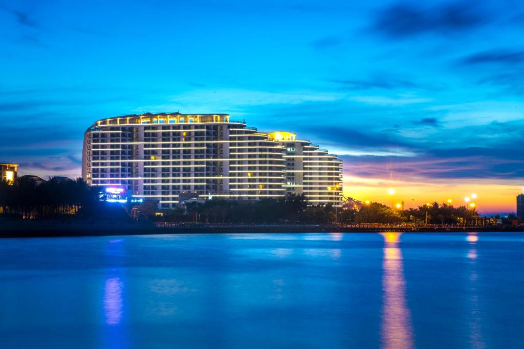 un grande edificio di fronte a un grande bacino d'acqua di Haikou Bay Hengda Yige Holiday Condo Hotel a Haikou