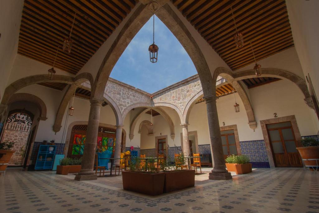 un bâtiment vide avec des arches, des tables et des plantes en pot dans l'établissement NaNa Vida Hotel Morelia, à Morelia