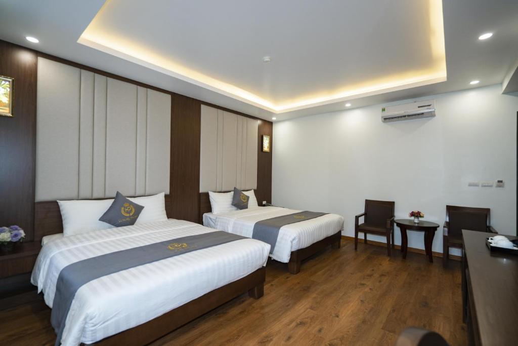 a hotel room with two beds and a desk at Luxury Palace Hotel in Ha Long