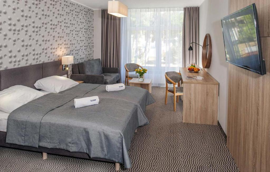 een hotelkamer met een bed en een stoel bij Akces Medical Fit & Spa in Dźwirzyno