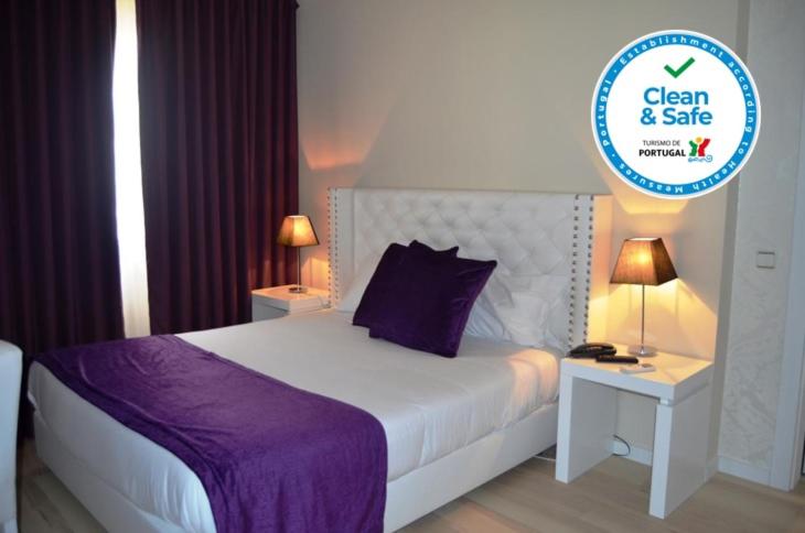 a bedroom with a large bed with a purple blanket at Hotel Torres Novas in Torres Novas