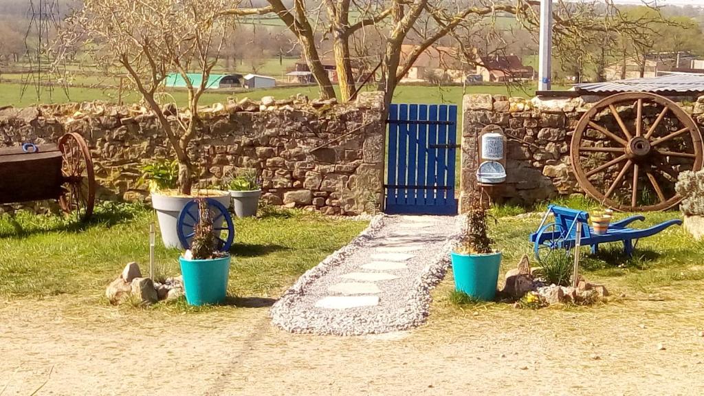 un jardin avec des arbres, une porte bleue et un mur en pierre dans l'établissement Domaine de La Madeleine, à Ygrande