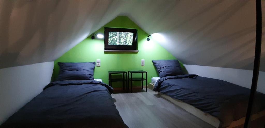 two beds in a room with a green wall at OSADA POD LASEM in Andrychów