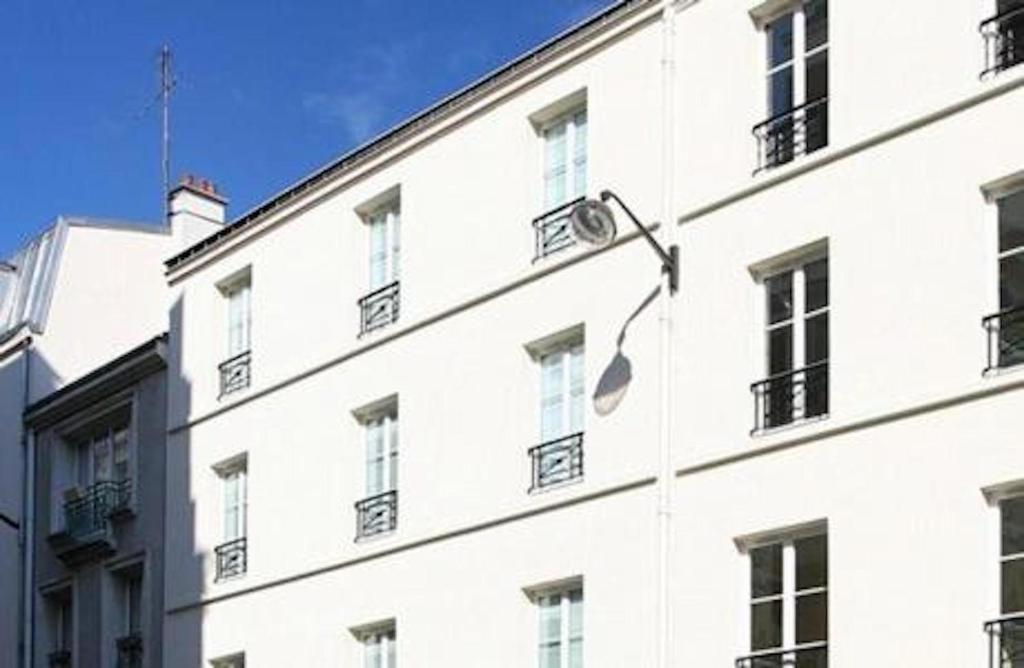 - un bâtiment blanc avec des fenêtres sur le côté dans l'établissement Hôtel Tingis, à Paris