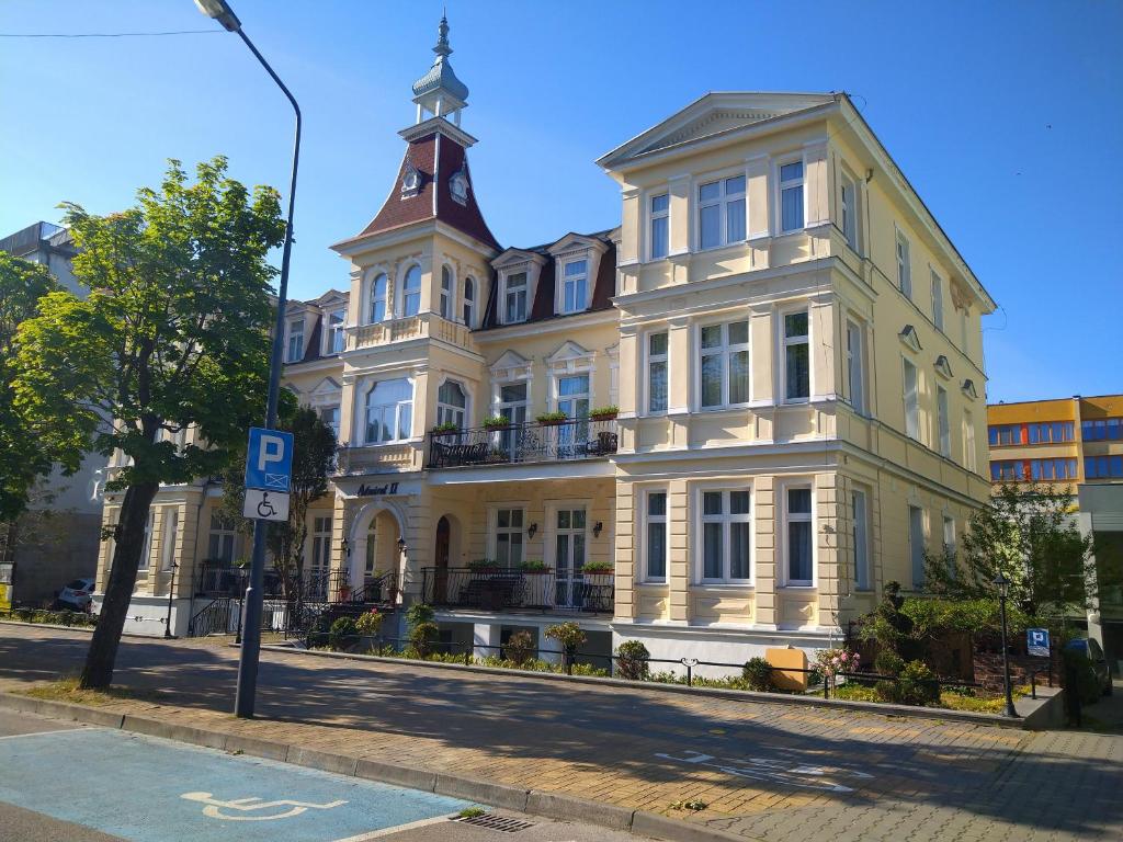 a large yellow building with a clock tower on a street at Admiral II in Świnoujście