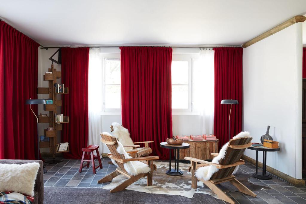 a living room with red curtains and rocking chairs at Grand Hotel Soleil d'Or in Megève