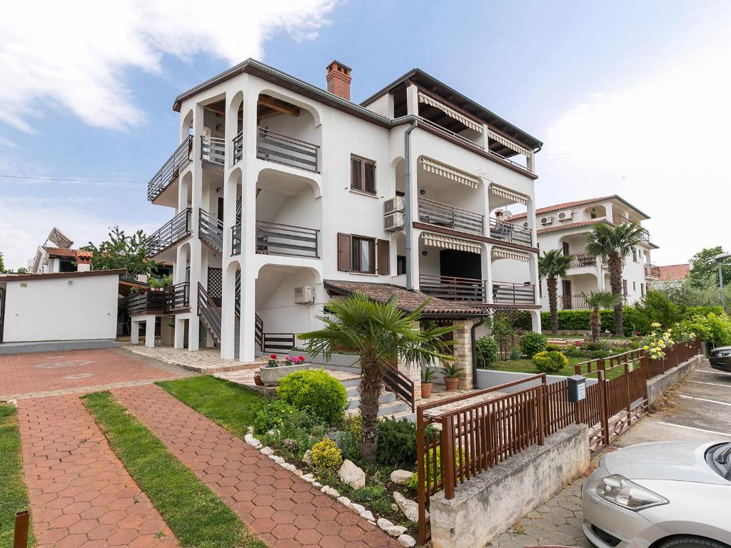 a white house with a fence in front of it at Apartments Špadići in Poreč