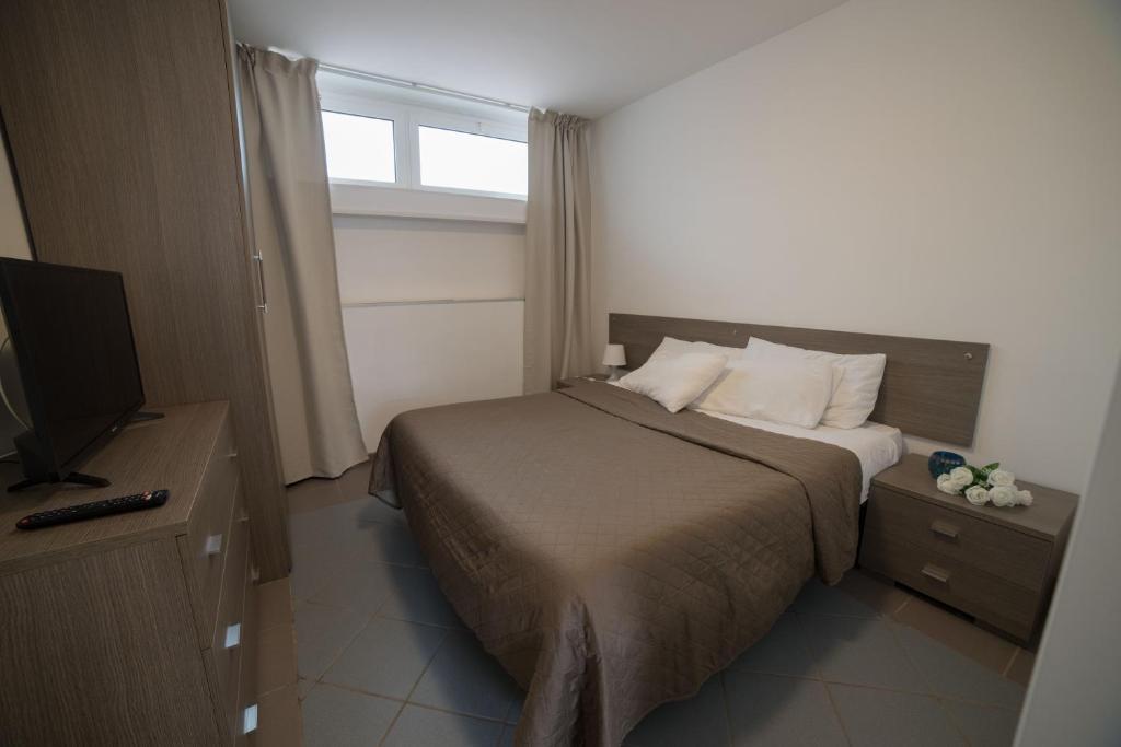 a bedroom with a bed with a television and a window at Villa Lara in Polignano a Mare