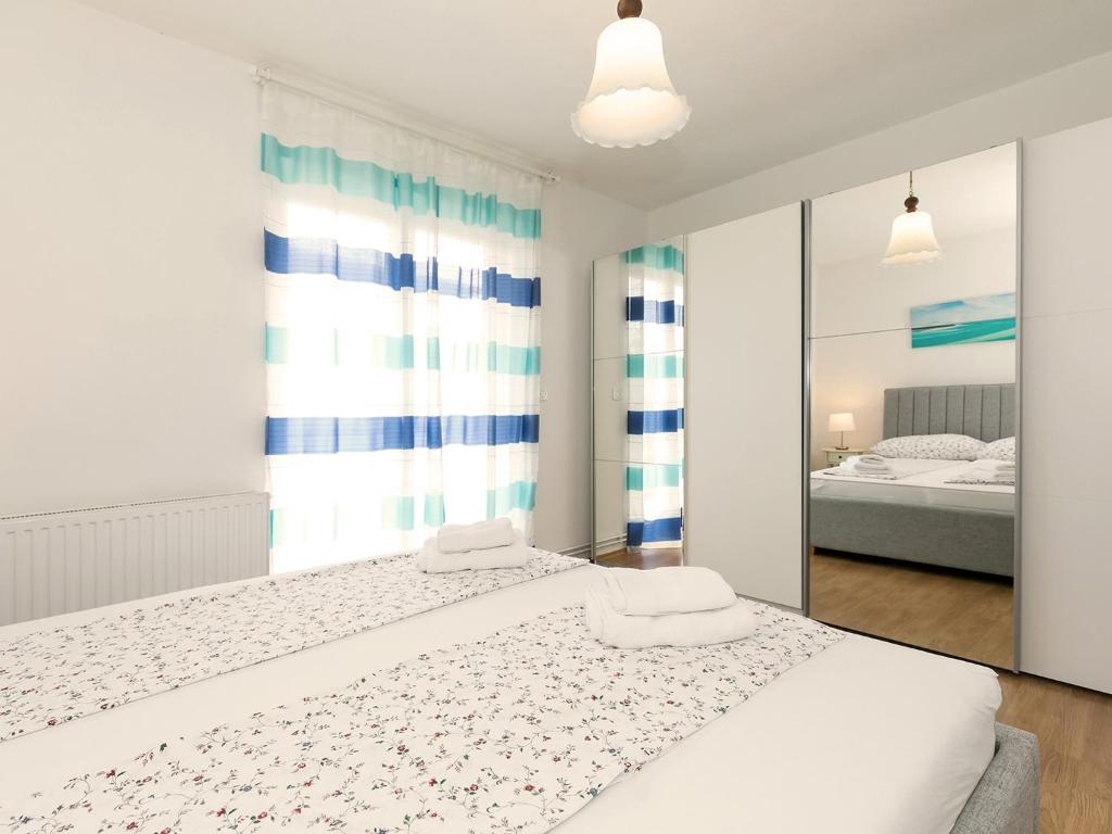 a white bedroom with a bed and a mirror at Apartments Špadići in Poreč