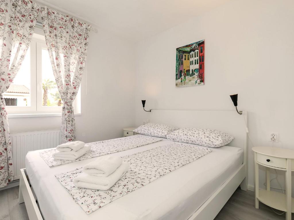 a white bedroom with two white towels on a bed at Apartments Špadići in Poreč