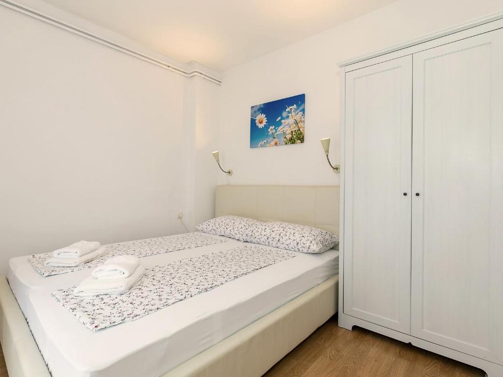a small white bedroom with a bed and a closet at Apartments Špadići in Poreč