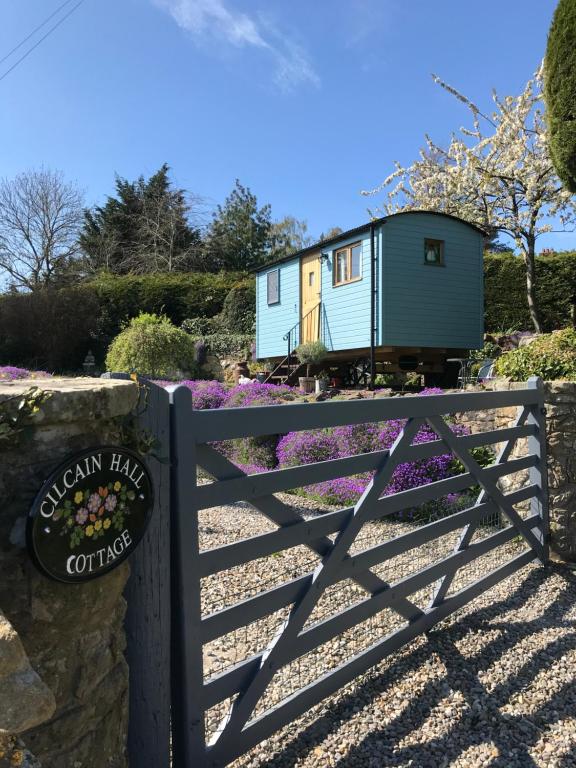 a tiny house sitting behind a fence with a sign at Shepherds Hut in the Hills - Nr. Mold in Nannerch