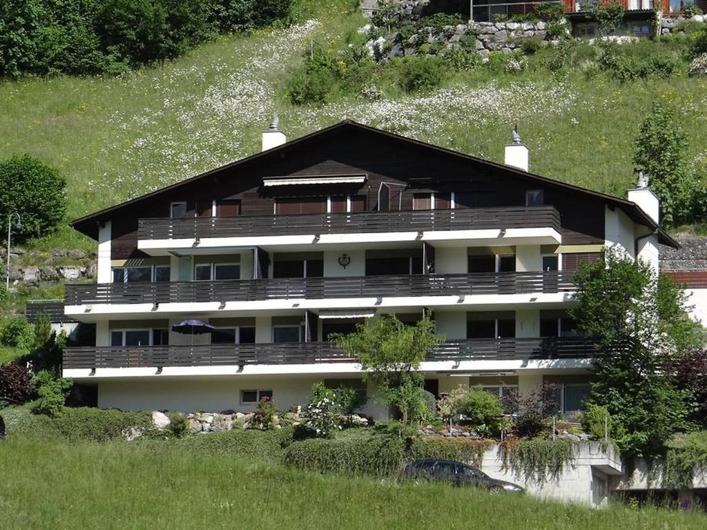 a large house on a hill with a grassy field at Apartment Zügstrasse 4 by Interhome in Engelberg