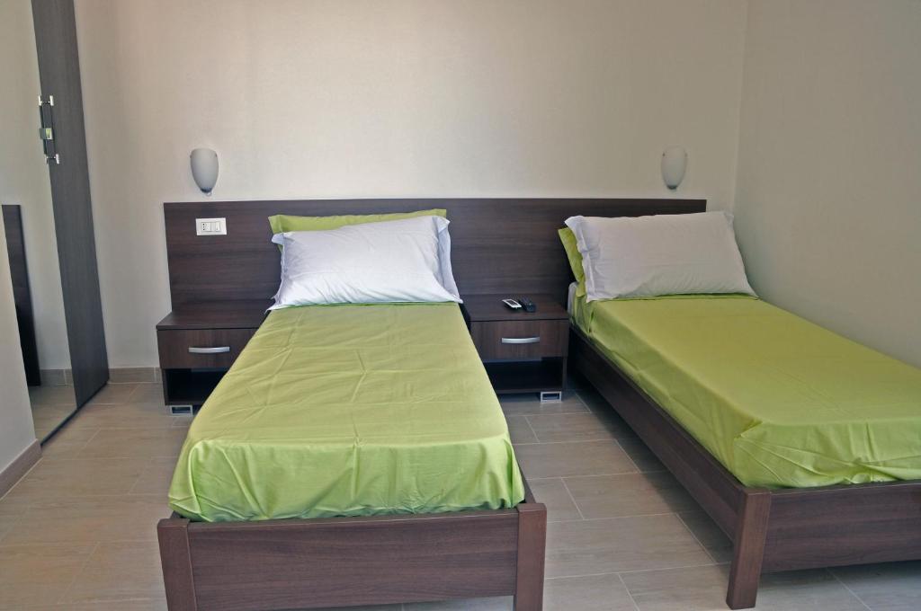 two beds in a room with green sheets at Villa Lara in Polignano a Mare