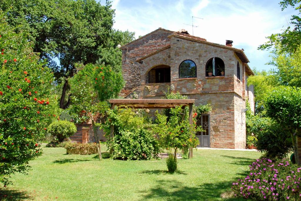 een oud stenen huis met een tuin ervoor bij Agriturismo Nibbiano in Montepulciano