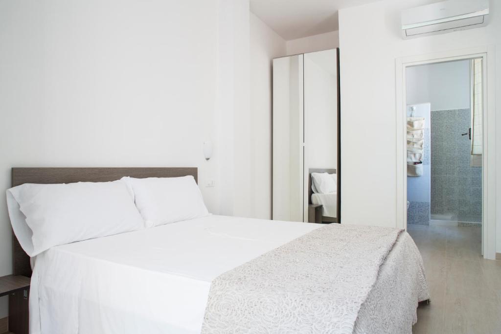 a white bedroom with a white bed and a mirror at Villa Lara in Polignano a Mare