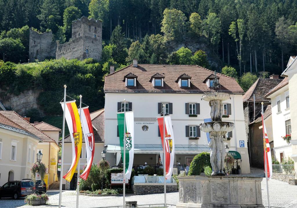 ein Gebäude mit Flaggen und einer Statue davor in der Unterkunft Villa Bucher - Metnitztalerhof in Friesach