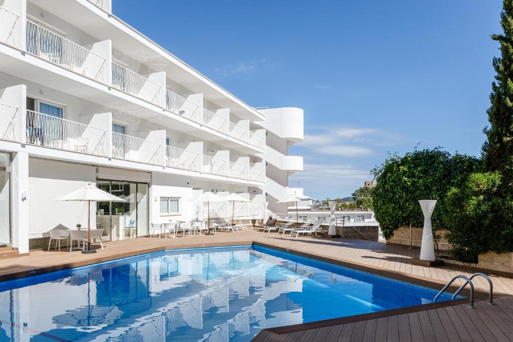 um hotel com piscina em frente a um edifício em Hotel Torá em Paguera