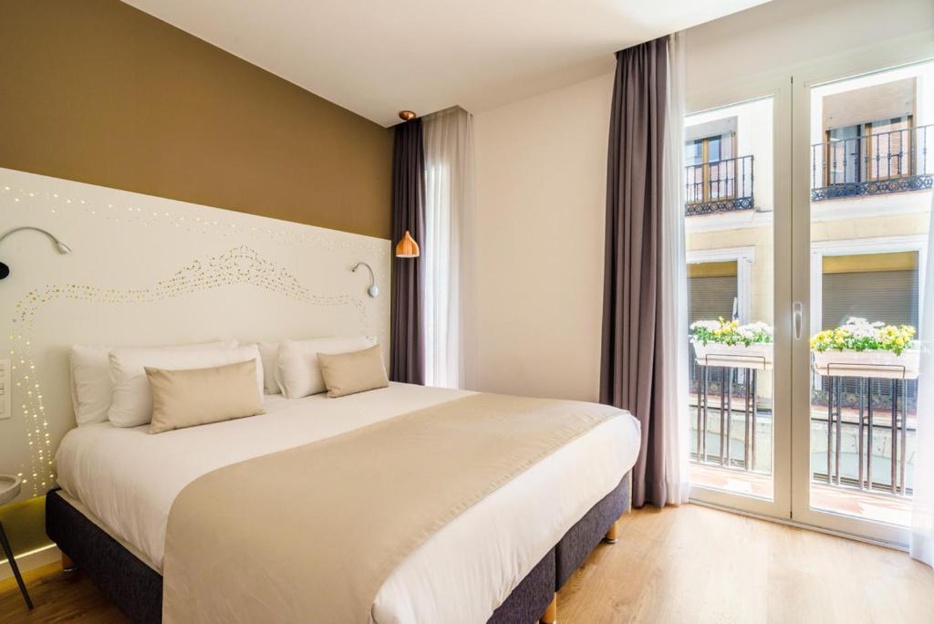 1 dormitorio con 1 cama grande y 2 ventanas en The Walt Madrid, en Madrid