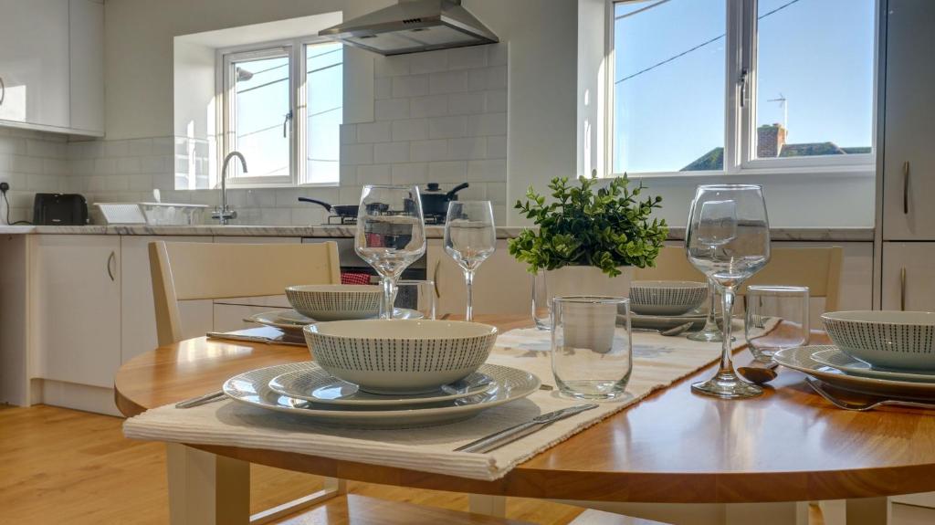 a table with wine glasses and plates on it in a kitchen at Didcot- Private Flat with Garden & Parking 03 in Didcot