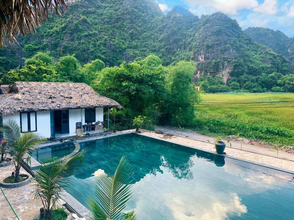a house with a swimming pool in front of a mountain at Ninh Binh Retreat in Ninh Binh