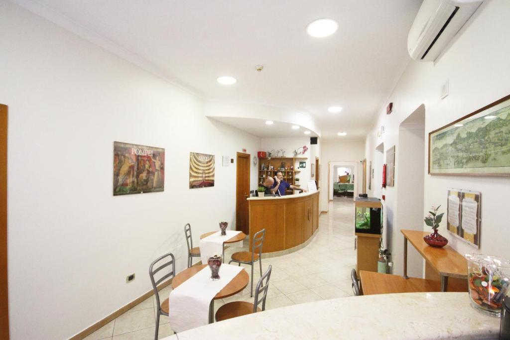 a dining room with tables and chairs and a kitchen at Hotel Zara Napoli in Naples