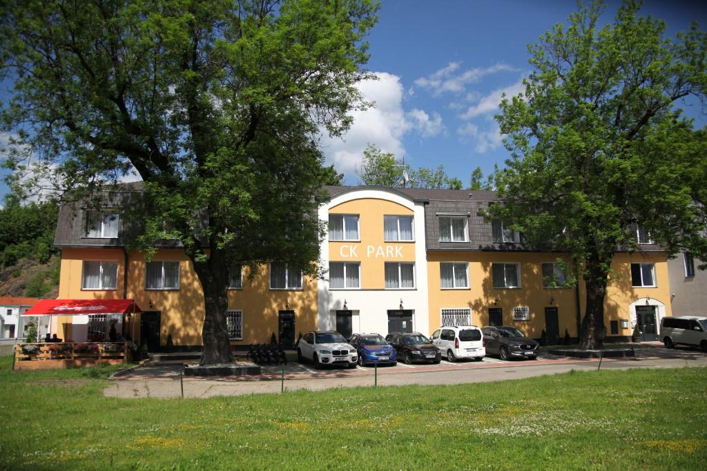 捷克克魯姆洛夫的住宿－Hotel CK Park，一座黄色的大建筑,停车场有车辆停放
