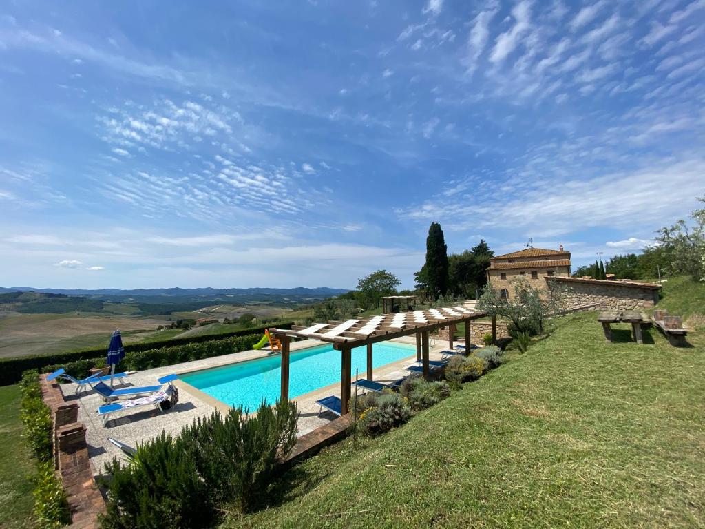 an outdoor swimming pool with a pergola next to a house at Agriturismo Casallario in Volterra