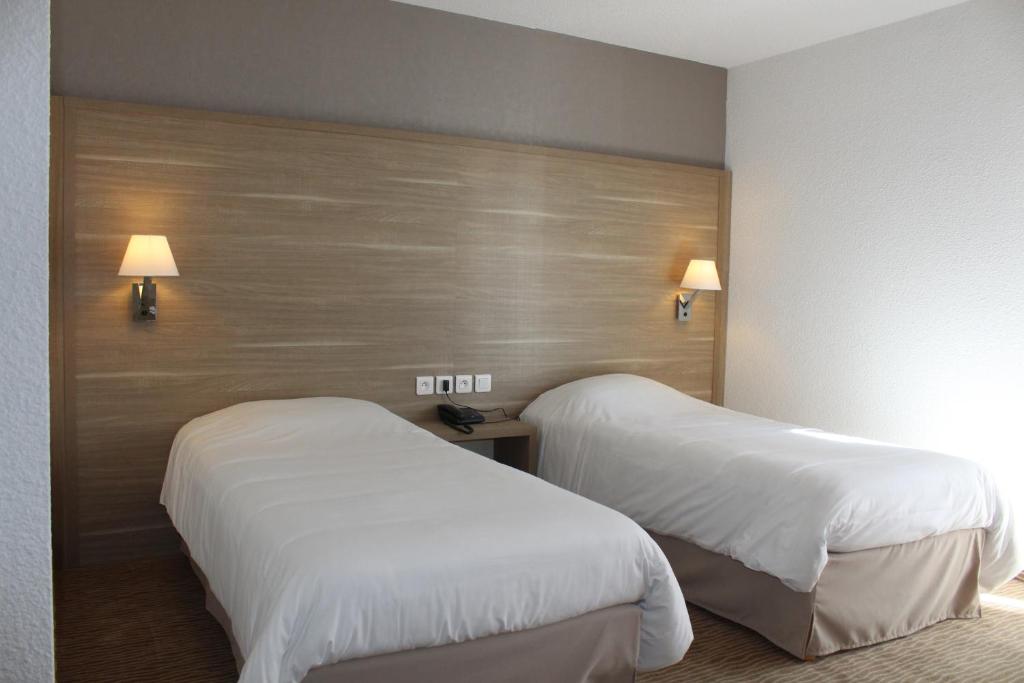 two beds in a hotel room with white sheets at Hotel Des Tilleuls in Dinard