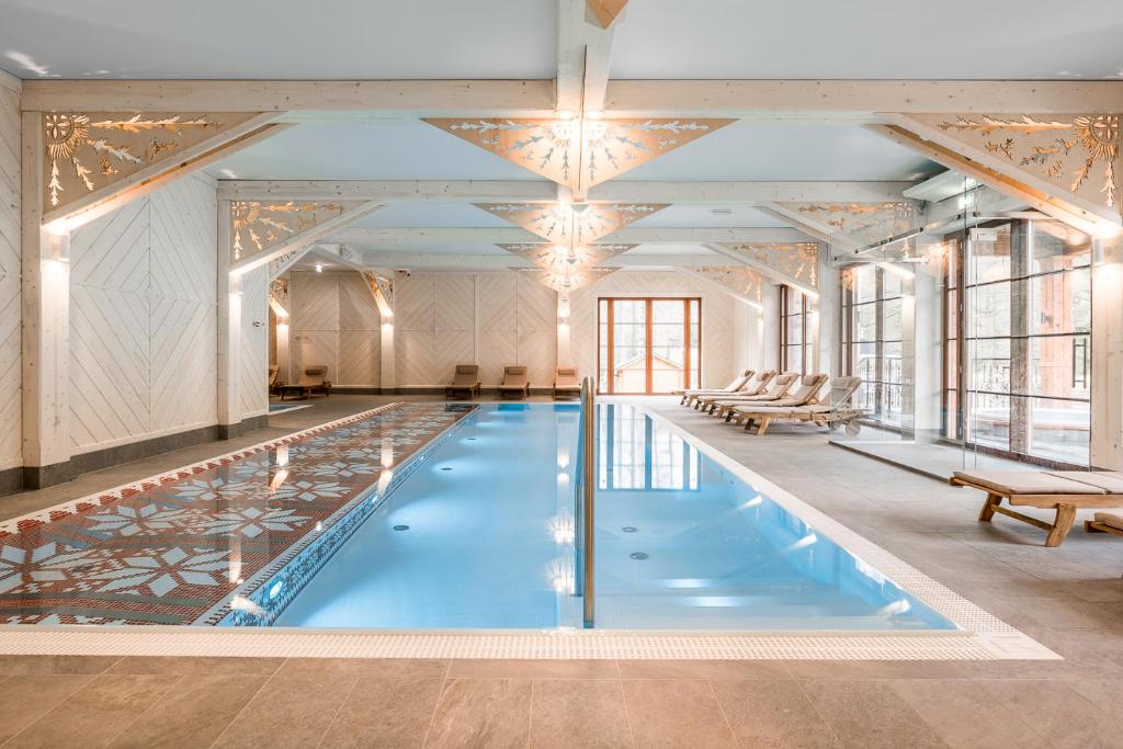 a large pool with blue water in a room with windows at Aries Hotel & SPA Wisła in Wisła