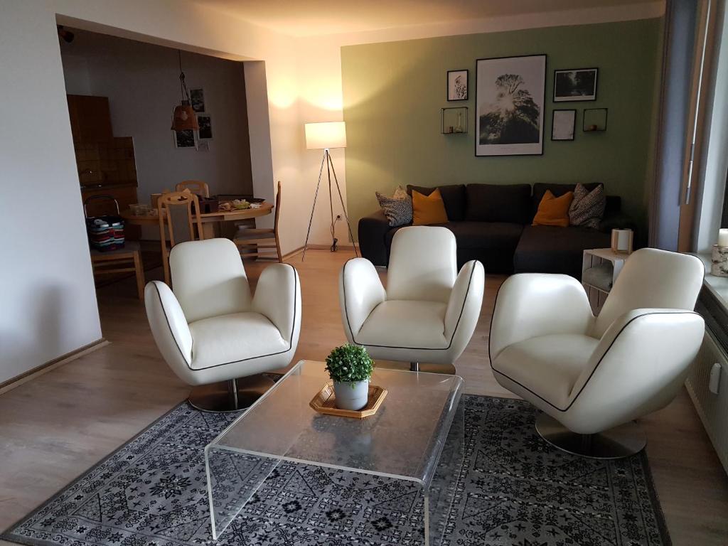 ein Wohnzimmer mit 2 weißen Stühlen und einem Tisch in der Unterkunft Ferienwohnungen Dora und Hansi in Braunlage