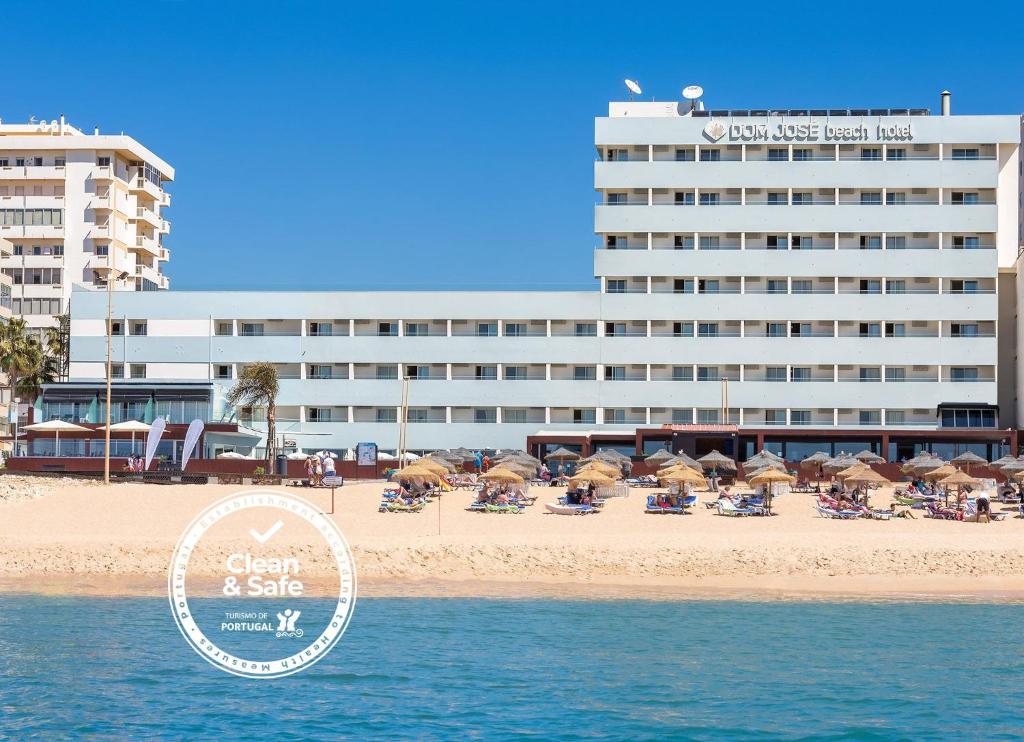 um hotel na praia com cadeiras e guarda-sóis em Dom Jose Beach Hotel (Plus) em Quarteira