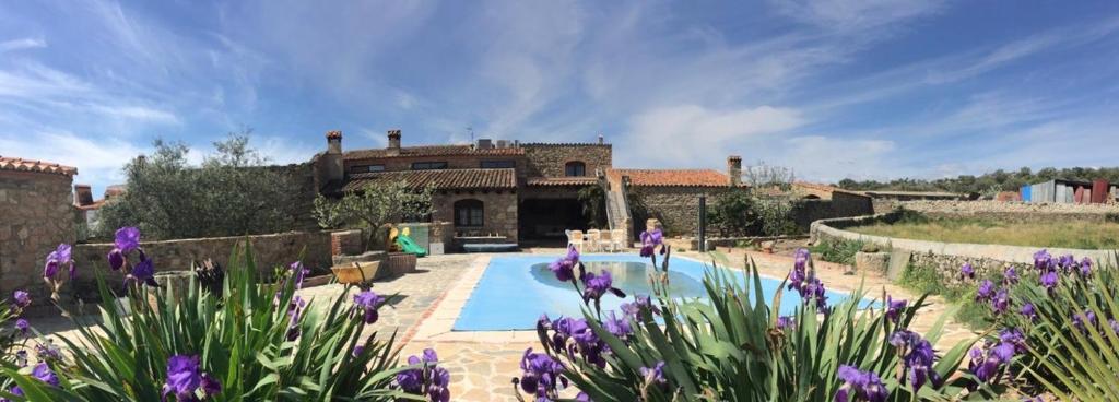 a house with a swimming pool and purple flowers at Casa - apartamento rural La Tahona del abuelo in Plasenzuela