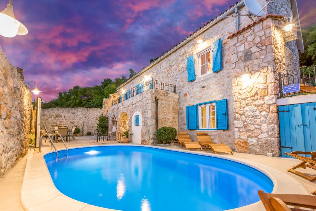 ein Haus mit einem Pool vor einem Gebäude in der Unterkunft Villa Toscana - Charming stone Villa with private pool & garden in Grižane