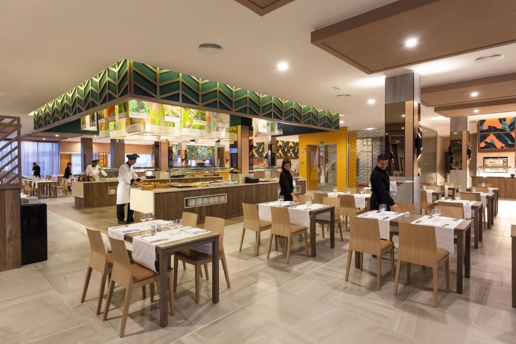 a restaurant with white tables and chairs and two chefs at Hotel Riu Vistamar Gran Canaria - All Inclusive in Puerto Rico de Gran Canaria
