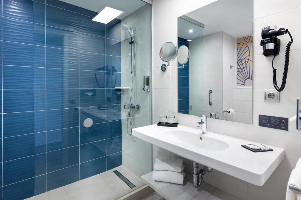 a bathroom with a sink and a shower with blue tiles at Hotel Riu Vistamar Gran Canaria - All Inclusive in Puerto Rico de Gran Canaria