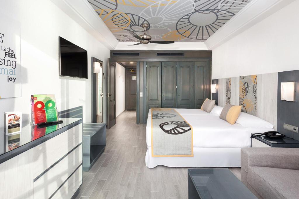 a hotel room with a bed and a couch at Hotel Riu Vistamar Gran Canaria - All Inclusive in Puerto Rico de Gran Canaria