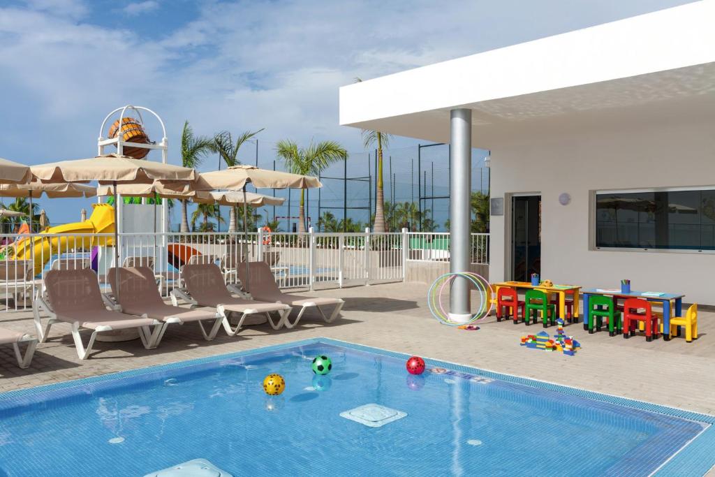 a swimming pool with chairs and a playground with a slide at Hotel Riu Vistamar Gran Canaria - All Inclusive in Puerto Rico de Gran Canaria