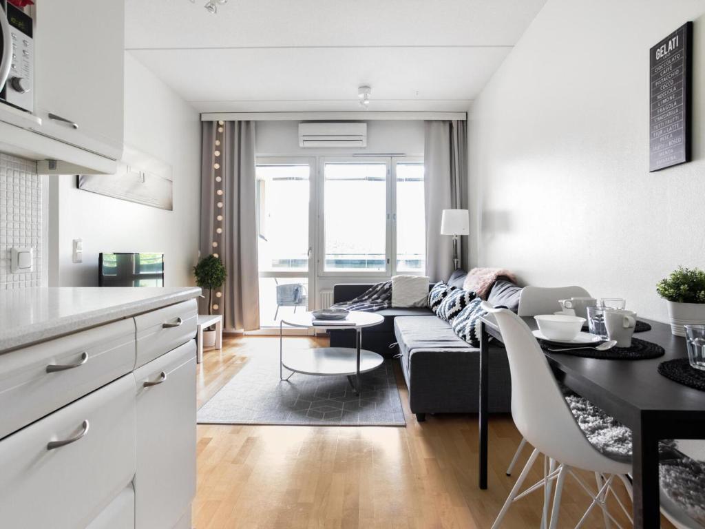 Kotimaailma Apartments Lahti في لاهتي: مطبخ وغرفة معيشة مع أريكة وطاولة