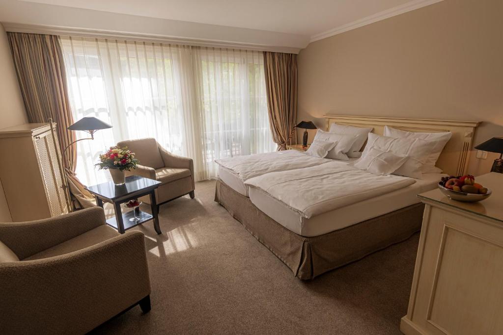 a hotel room with a large bed and a chair at Strandhotel Fontana in Timmendorfer Strand