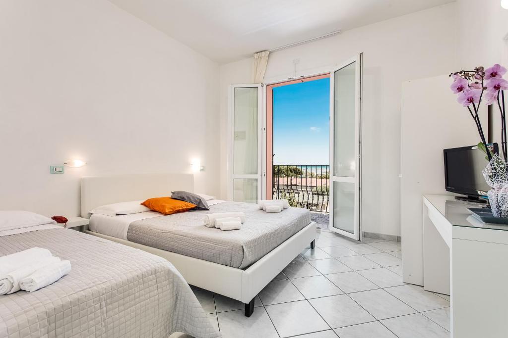 a bedroom with two beds and a television and a balcony at Mare Home in Cesenatico