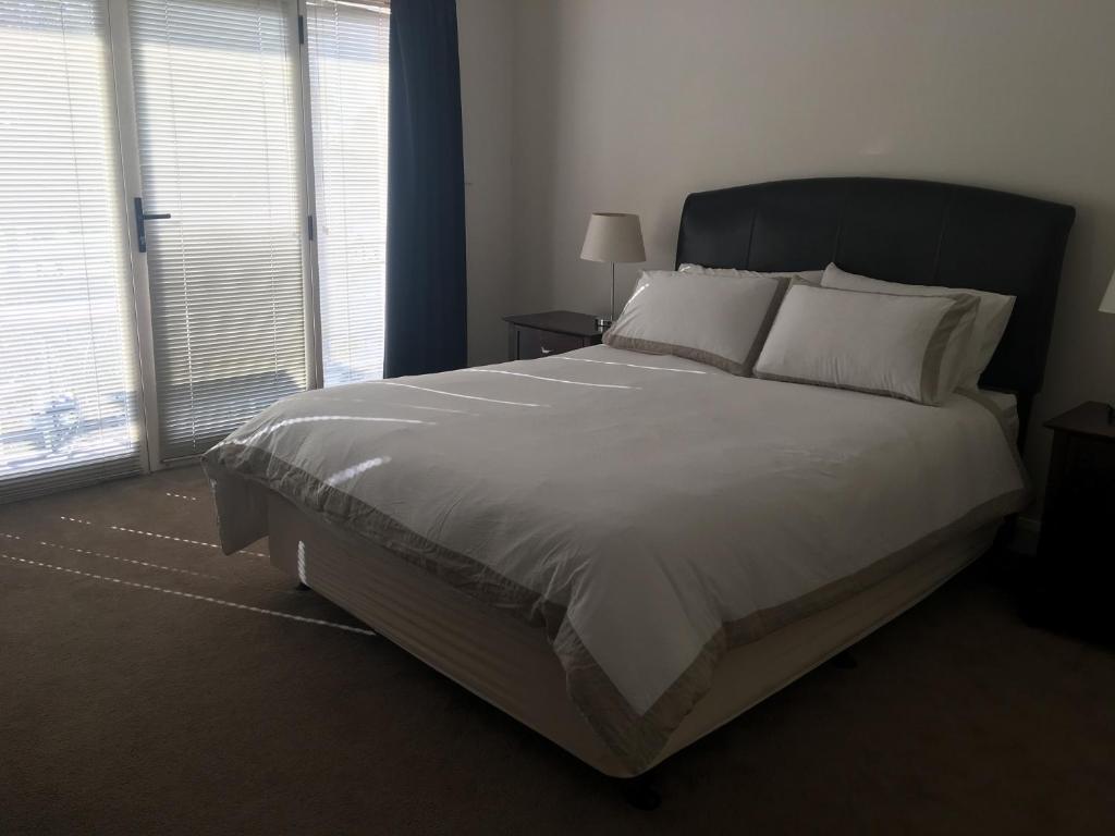 a bedroom with a large bed with white sheets and pillows at Travers Street Apartment in Wagga Wagga