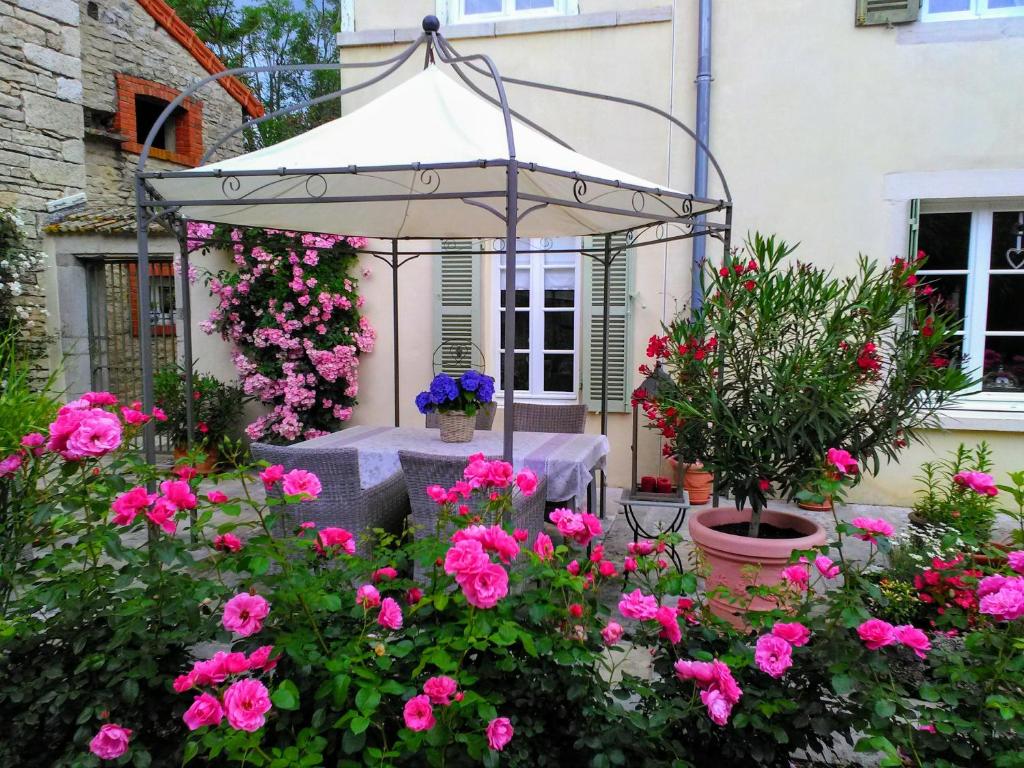 an umbrella in a garden with pink flowers at Ancien Domain "Le petit Bonheur" in Tailly