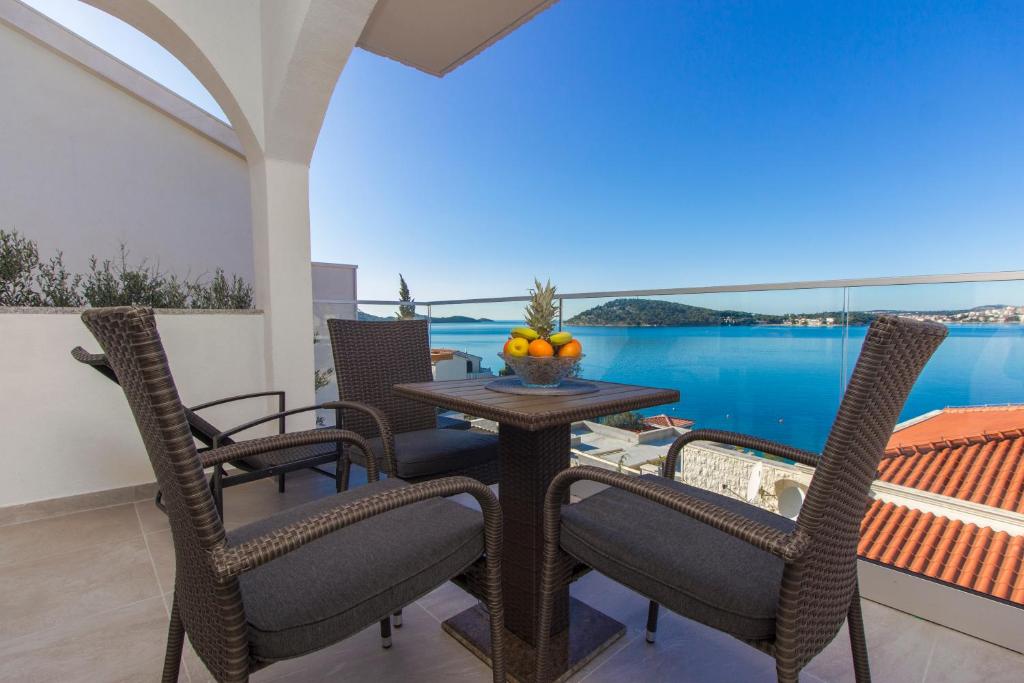 einen Tisch und Stühle auf einem Balkon mit Blick auf das Wasser in der Unterkunft Apartmani Malis in Ražanj