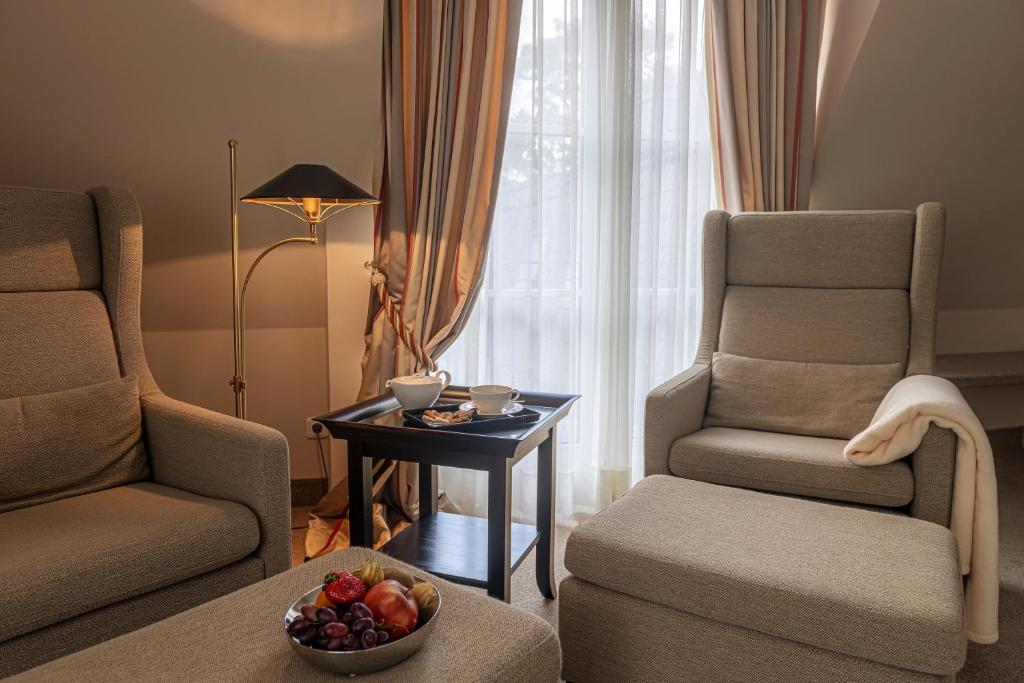 a living room with two chairs and a table with a bowl of fruit at Strandhotel Fontana in Timmendorfer Strand